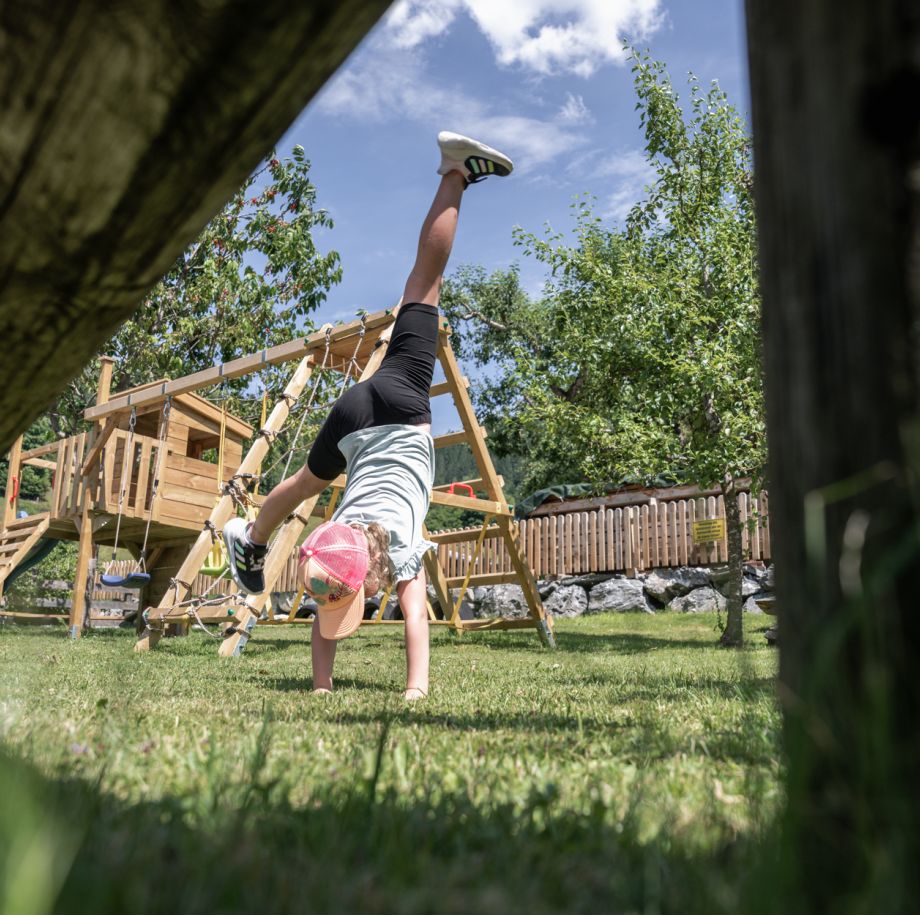 Kind macht einen Handstand auf dem Spielplatz des Tobhartbauers