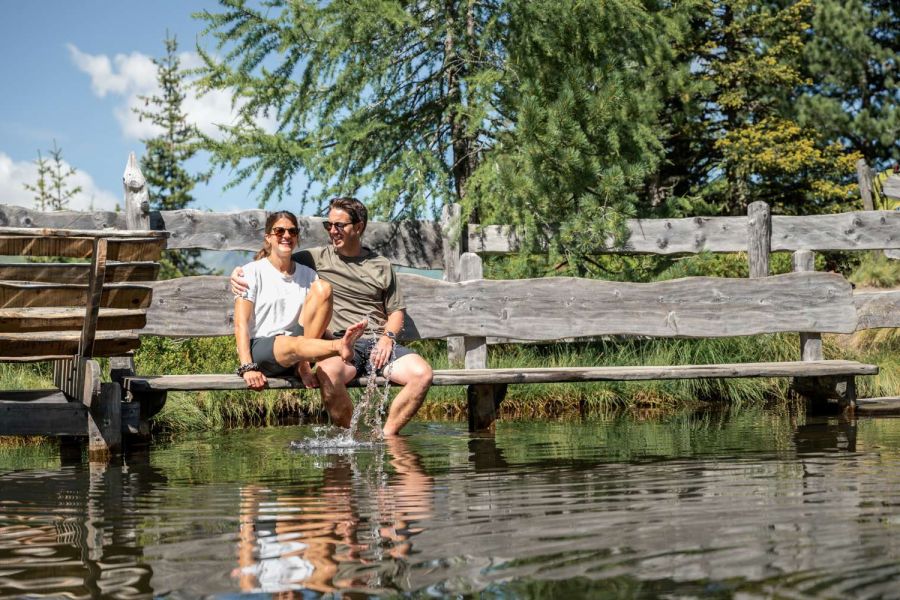Paar entspannt mit den Füßen im Wasser an einem Bergsee im Gasteinertal