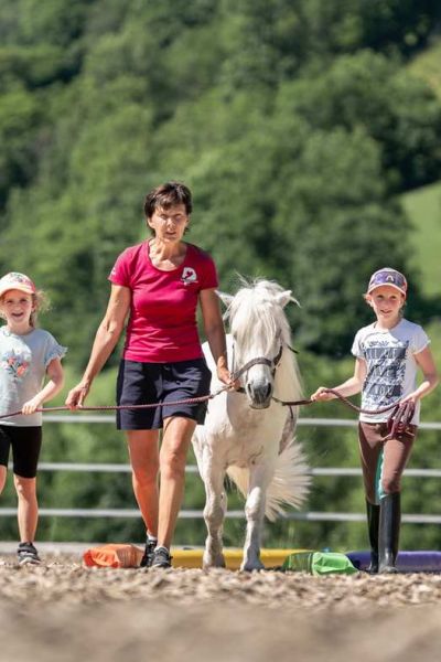 Reitpädagogin Ilona Hutter mit zwei Kindern und einem weißen Pony
