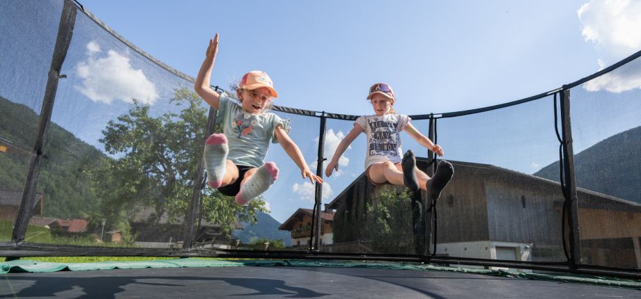 Zwei Kinder springen auf dem Trampolin am Tobhartbauer