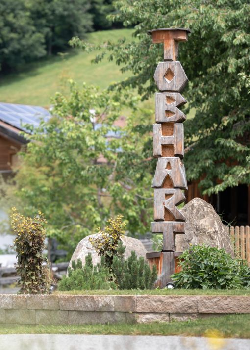 Holzskulptur mit dem Schriftzug Tobhart im Garten des Bauernhofs in Dorfgastein