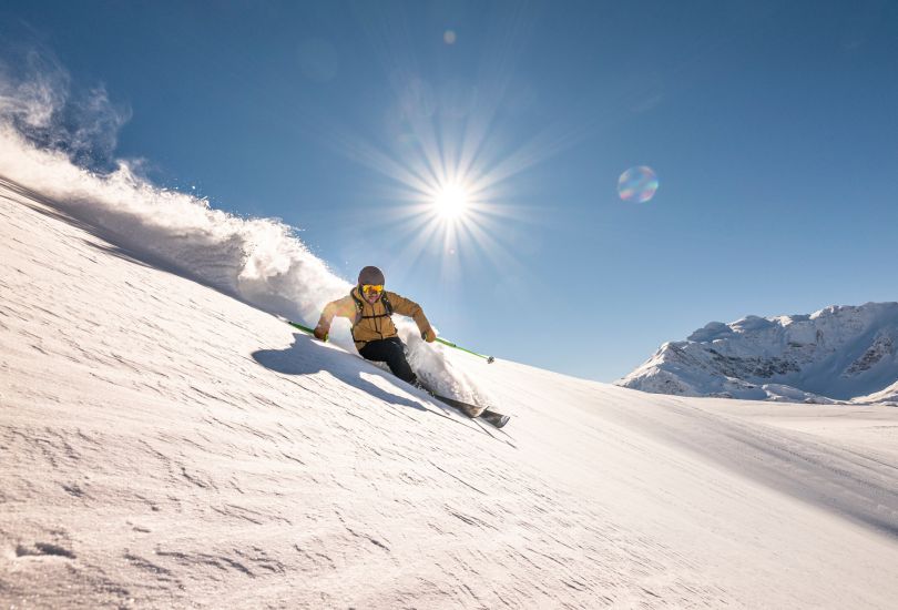 Skifahrer im Tiefschnee vor alpiner Bergkulisse
