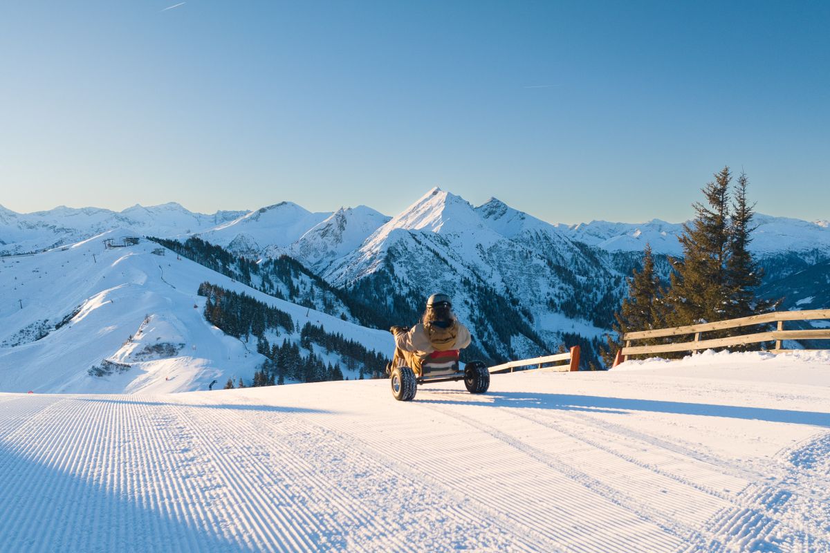 Mountaincart-Fahrt auf verschneiter Piste vor Bergkulisse in Dorfgastein