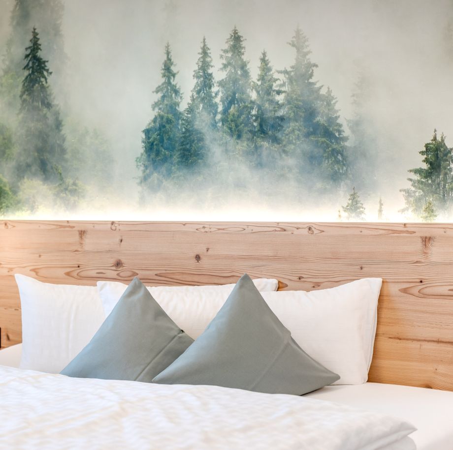 Gemütliches Doppelbett mit Bergmotiv in einer Ferienwohnung