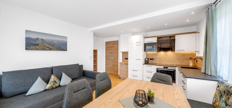 Wohnküche mit Sofa und Esstisch in einer Ferienwohnung des Tobhartbauers