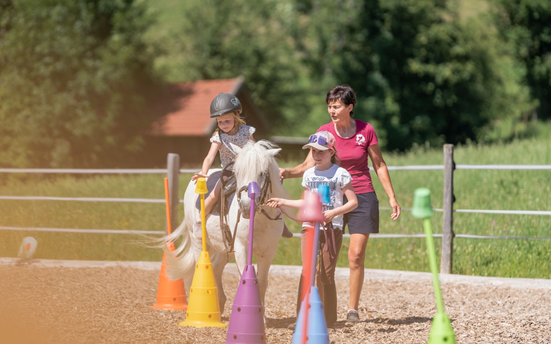 Kind reitet unter Anleitung durch einen Parcours am Tobhartbauer