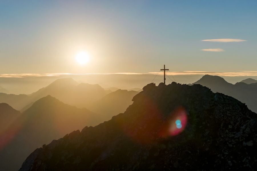 Sonnenaufgang am Gipfelkreuz über der Bergwelt des Gasteinertals